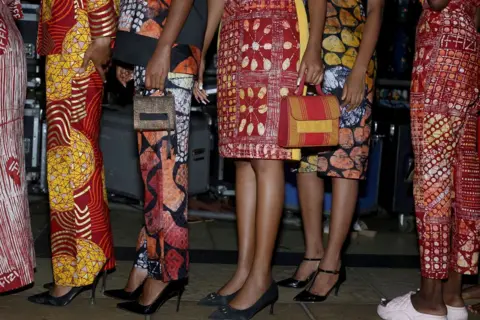 Emmanuel Adegboye / EPA Women stand close together in a queue. They are only visible from the waist down. They wear knee-length skirts and straight-leg trousers. In Lagos, Nigeria - Saturday 7 December 2024
