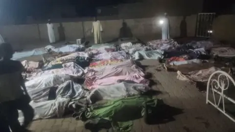 Social media Dead bodies lay out in the mosque courtyard. They are covered by cloth as men stand around. 