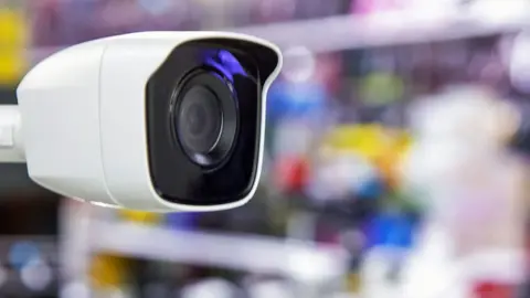 Getty Images Close-up of a CCTV with a blurred background of goods on shop shelves