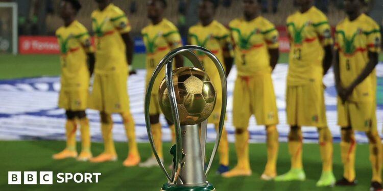 Mali players dressed in yellow, green and red kit stand behind the African Nations Championship (CHAN) trophy ahead of the final against Morocco in Cameroon in 2021.