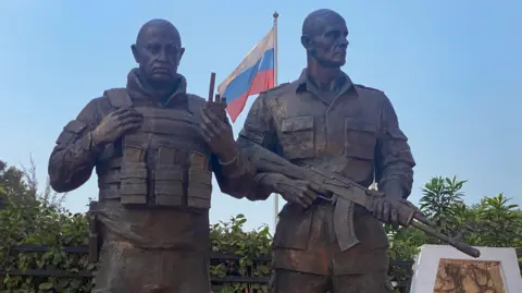 AFP A bronze statue in the likeness of the late Wagner private mercenary group chief Yevgeny Prigozhin (L), and his right-hand man Dmitru Utkin (R), erected in front of the Maison Russe Russian House in Bangui.