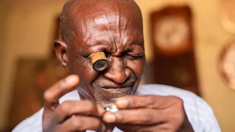 Ifiokabasi Ettang / BBC A close-up of Bala Muhammad looking at a watch through a special eye-glass in his right eye