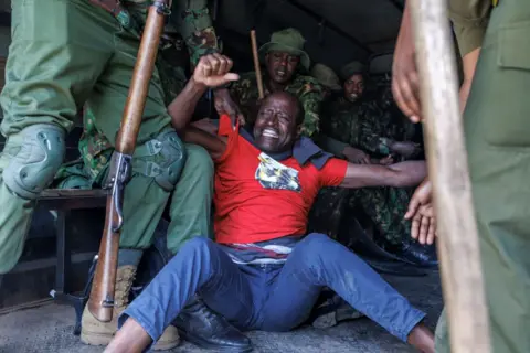 Tony Karumba / AFP A Kenyan man is held by police officers in a vehicle for demanding the release of government critics abducted in the country - Monday 6 January 2025