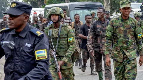 Reuters A Rwandan policeman and Rwandan army soldiers escort a group of Congolese soldiers into Gisenyi after they surrendered