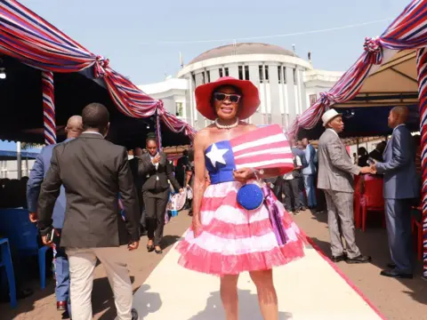 MATTHEW JACOBS / AFP A woman stands outside the capitol building wearing a dress modelled after the Liberian flag.