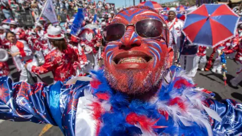 EPA A man with blue, red and white face paint smiles broadly at Cape Town's Tweede Nuwe Jaar festival - Saturday 4 January 2025