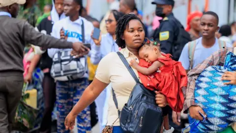 EPA Refugees carry their belongings after crossing the border from Goma in the Democratic Republic of Congo to Gisenyi, Rwanda, 27 January 2025