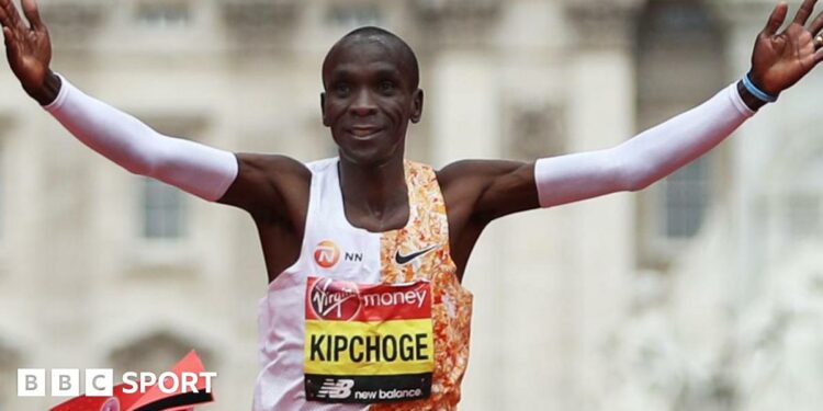 Eliud Kipchoge with his arms outstretched in celebration as he crosses the line to win the London Marathon