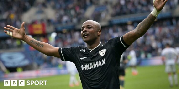 Ghana forward Andre Ayew, playing for French side Le Havre in a black top, spreads his arms out wide while celebrating a goal for his team